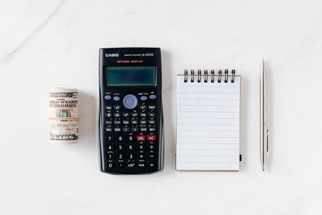 Notizbuch, Stift und Taschenrechner beim Ausrechnen der Quersumme